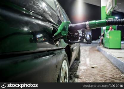 Fueling nozzles at filling station close up at night
