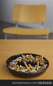 Full ashtray of cigarettes on table