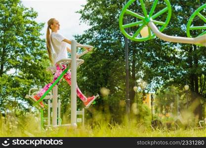 Full body of woman working out in outdoor gym. Girl doing legs exercises on street public equipment on sunny day. Woman doing exercise in outdoor gym