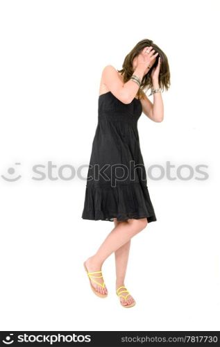 Full body portrait of a young brunette woman in a black summer dress, covering her head with her hands, laughing, and very much self-aware