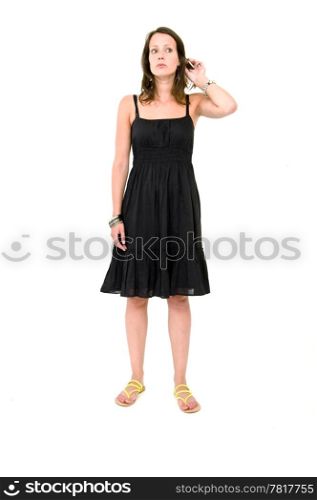 Full body portrait of a young brunette woman in a black summer dress, lifting her hear and listening