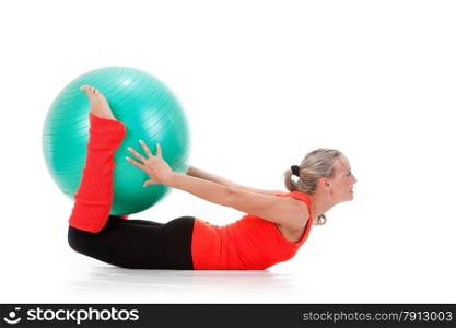 Full body shot of a smiling woman lying down the floor and holding the pilates ball with her legs and hands . Orange, green and black colors