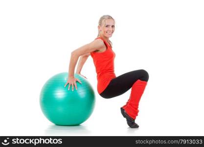 Full body shot of a smiling woman sitting on her knees and balancing on the fitness ball. Orange, green and black colors