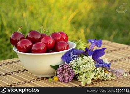 Full bowl of ripe cherries with wild forest flowers. bowl of cherries