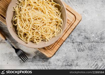 Full bowl with boiled spaghetti on a cutting board. On a gray background. High quality photo. Full bowl with boiled spaghetti on a cutting board.