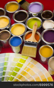 Full Buckets of rainbow colored oil paint on red background