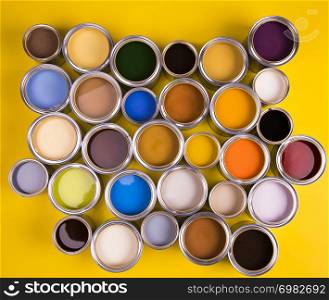 Full Buckets of rainbow colored oil paint on yellow background