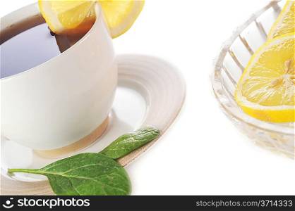 full cup of tea with lemon and greens leaves