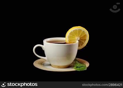 full cup of tea with lemon and greens leaves on black