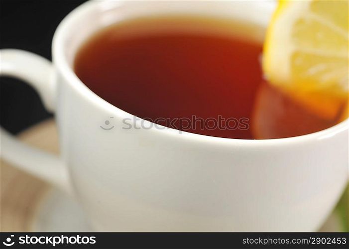 full cup of tea with lemon and on black