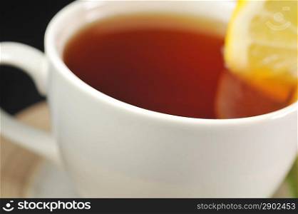 full cup of tea with lemon and on black