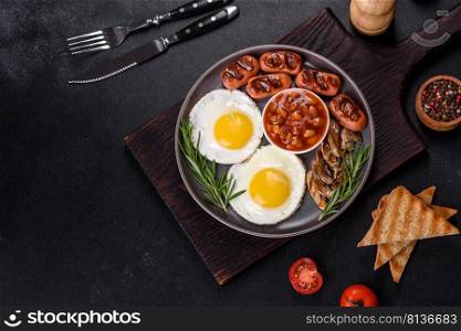 Full english breakfast - bean, fried eggs, roasted sausa≥s, tomatoes,μshrooms on a dark concrete tab≤with toasted bread. Full english breakfast with bean, fried eggs, roasted sausa≥s, tomatoes andμshrooms