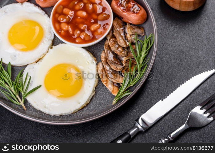 Full english breakfast - bean, fried eggs, roasted sausages, tomatoes, mushrooms on a dark concrete table with toasted bread. Full english breakfast with bean, fried eggs, roasted sausages, tomatoes and mushrooms