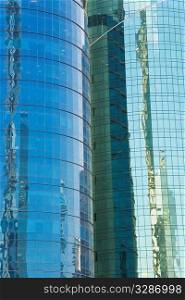 Full frame shot of tall glass clad modern buildings with reflections of surrounding similar structures