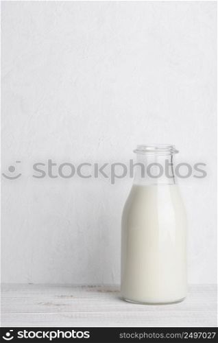 Full glass bottle of milk on white wooden table background vertical compositionl with copy space