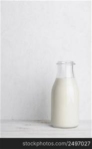 Full glass bottle of milk on white wooden table background vertical compositionl with copy space