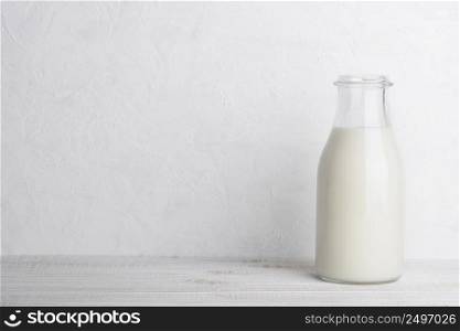 Full glass bottle of milk on white wooden table background with copy space