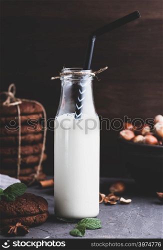 full glass bottle with milk and a black straw, vintage toning