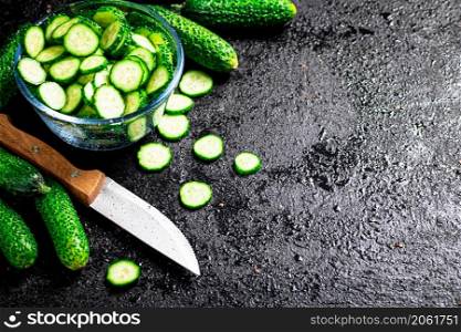 Full glass bowl of chopped fresh cucumbers. On a black background. High quality photo. Full glass bowl of chopped fresh cucumbers.