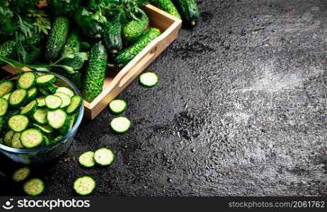 Full glass bowl of chopped fresh cucumbers. On a black background. High quality photo. Full glass bowl of chopped fresh cucumbers.