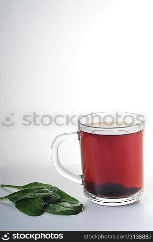 Full glass cup of tea and greens leaves