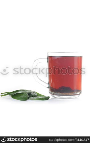 Full glass cup of tea and greens leaves