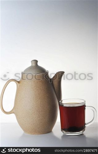 Full glass cup of tea and teapot