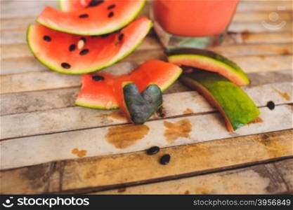 Full glass of a creamy and bubbly watermelon shake smoothie with a slice of watermelon and glass tube. Sliced watermelon and paper decorative on brown wood board background in rustic style.. Waternelon shape heart