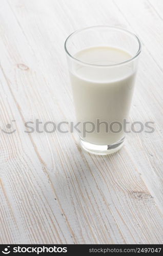 Full glass of milk on white wooden table