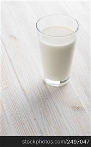 Full glass of milk on white wooden table