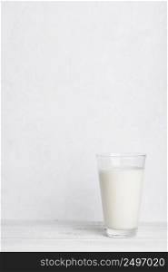 Full glass of milk on white wooden table background vertical with copy space