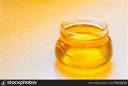 full honey pot glass, jar of organic floral honey on table