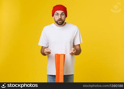 Full isolated studio picture from a young man opening shopping bags. Isolate over yellow background. Full isolated studio picture from a young man opening shopping bags. Isolate over yellow background.