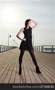 Full length attractive young woman posing on the pier in the morning