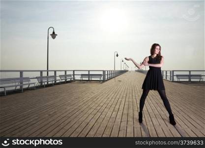 Full length attractive young woman posing on the pier in the morning
