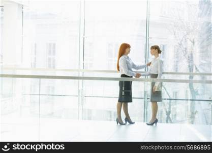 Full-length businesswomen shaking hands in office