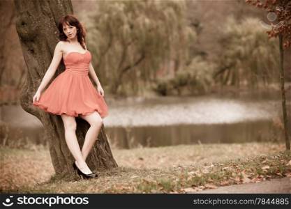 Full length fashionable young woman in red dress outdoor relaxing in park