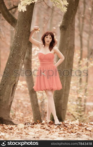 Full length fashionable young woman in red dress outdoor relaxing walking in park vintage photo sepia tone