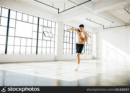 Full length front view of young man in gym in boxing stance