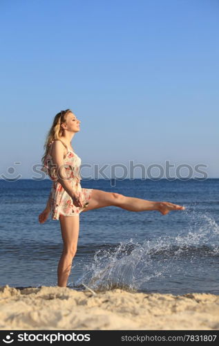 Full length happy girl playing with water at the summer beach.