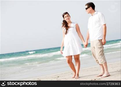 full length image of Young couple holding hands and walking on the beach