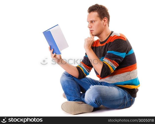 Full length male student sitting on floor reading a book preparing for exam isolated on white background