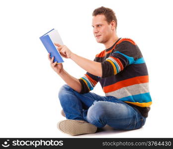 Full length male student sitting on floor reading a book preparing for exam isolated on white background