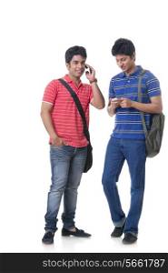 Full length male students using mobile phone against white background