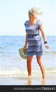 Full length mature woman with hat on beach enjoying summer holiday