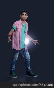 Full length of a confident teenage boy dancing against black background