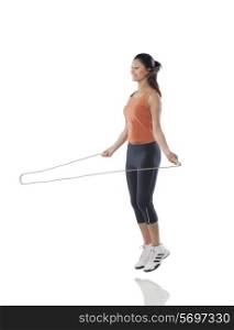 Full length of a fitness woman exercising with jump rope over white background