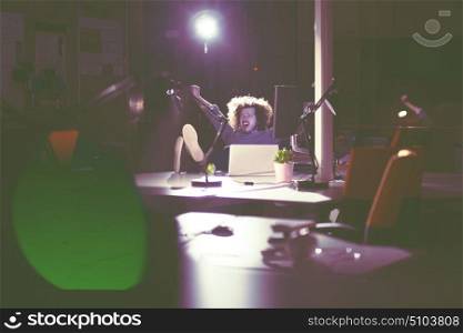 Full length of a relaxed casual young businessman sitting with legs on desk at night office
