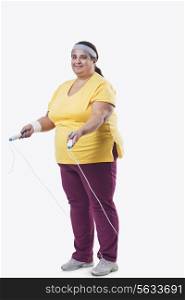 Full length of an overweight female with skipping rope over white background