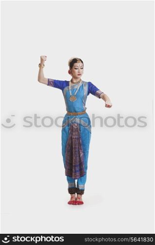 Full length of beautiful dancer performing Bharatanatyam against white background